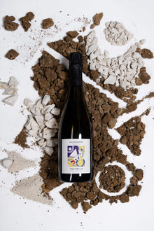 Eine Flasche des Winzerchampagners La Charbauterie von Hélène Charbaut wird umrahmt von Kalk- und Kreidesteinen die den Boden repräsentieren sollen auf dem die Trauben wachsen.